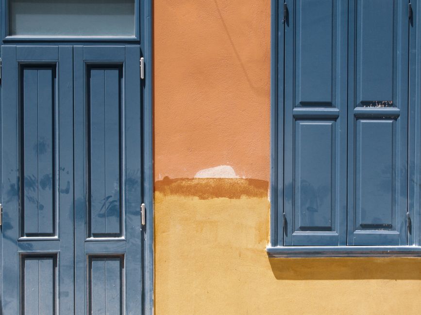 Orange painted wall with a blue door and window.