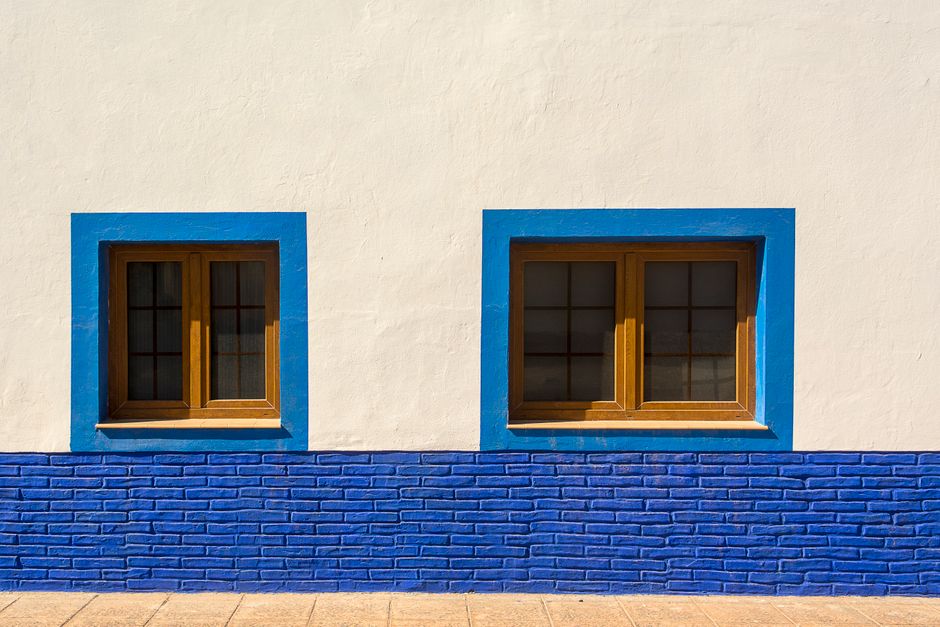 Blue-framed windows set in a white painted wall.